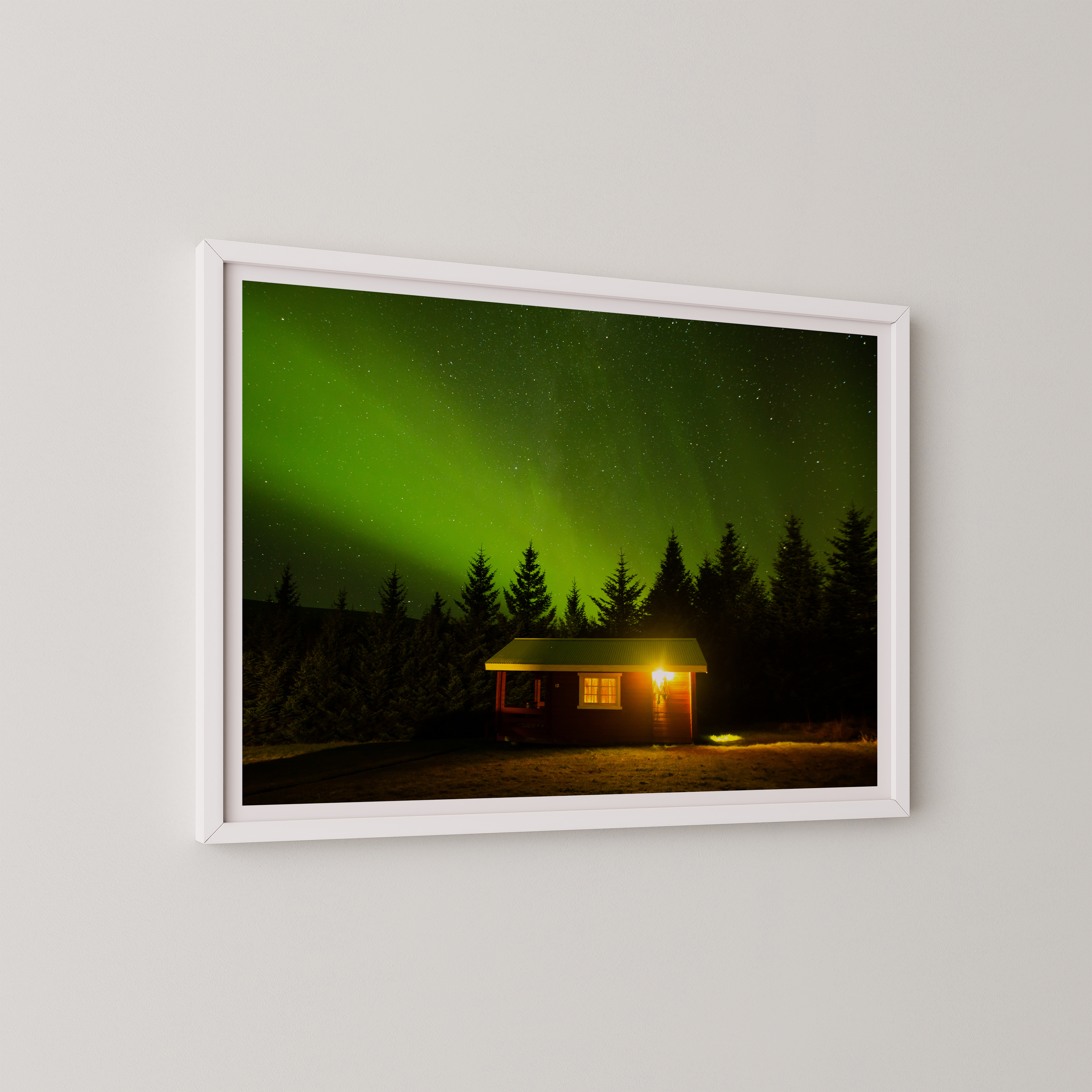 צילום אומנותי של בקתה מוארת בלב היער תחת מופע הזוהר הצפוני באיסלנד, מאת הצלם דניאל עובדיה.