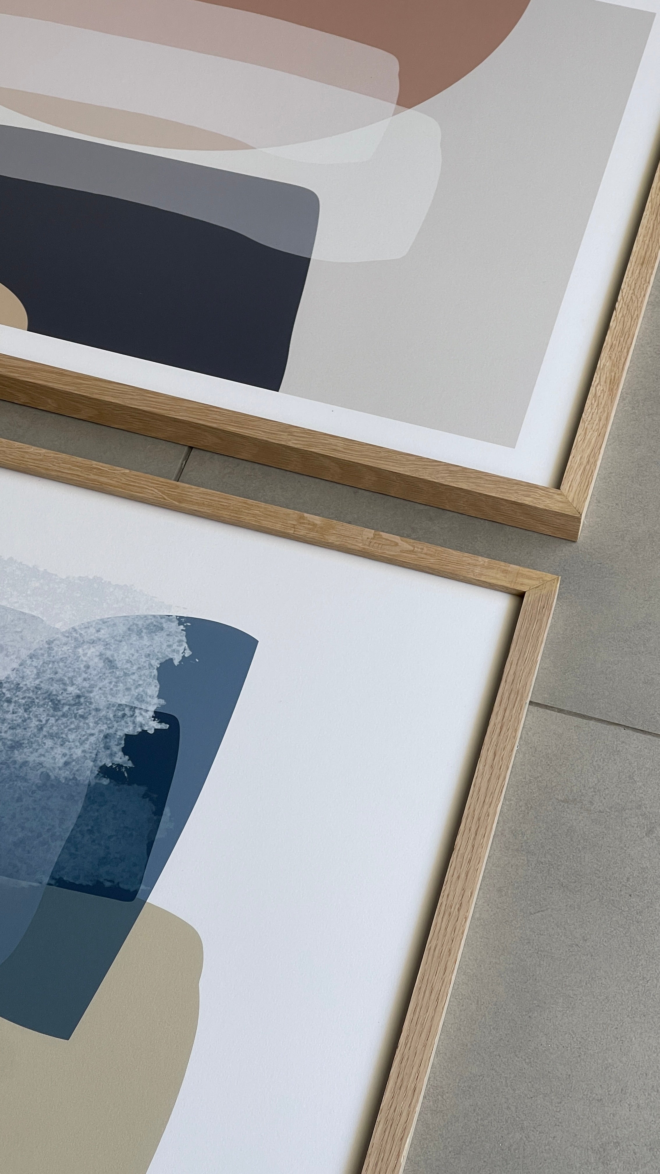 סט של שני פוסטרים ממוסגרים בסגנון אבסטרקטי, עם צורות אורגניות בגווני בז', כחול עמוק ואפרסק, המשדרים הרמוניה ורוגע.