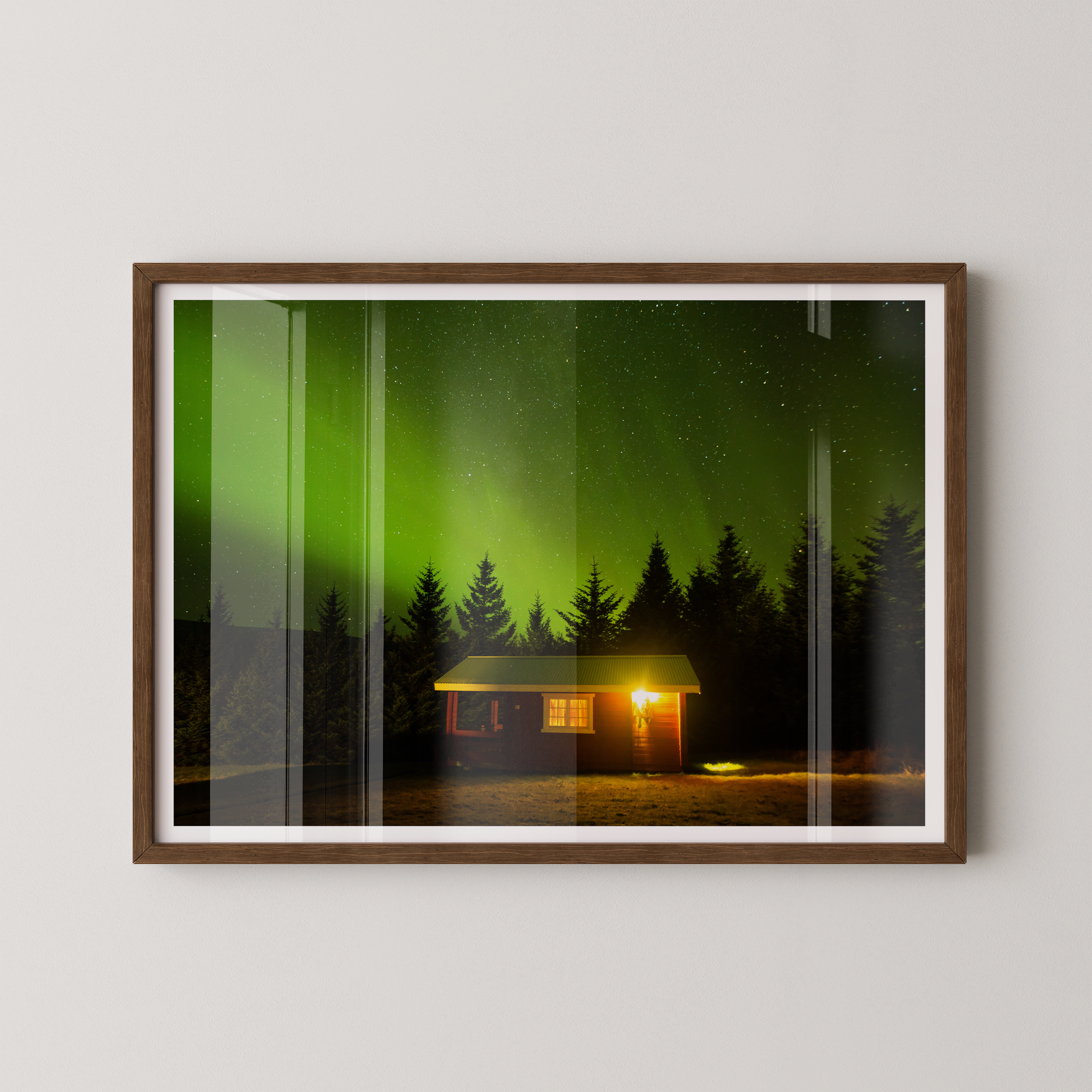 צילום אומנותי של בקתה מוארת בלב היער תחת מופע הזוהר הצפוני באיסלנד, מאת הצלם דניאל עובדיה.