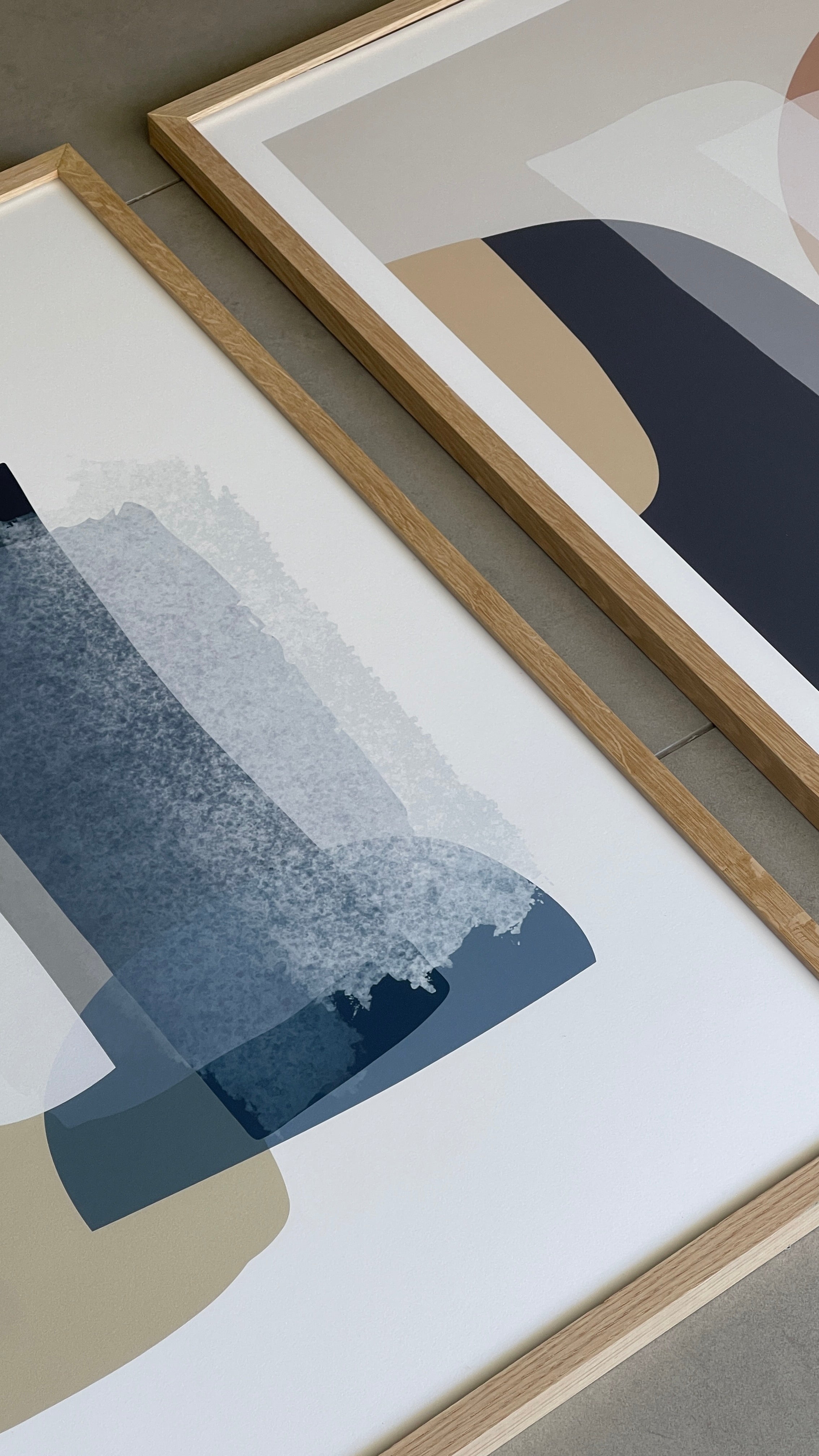 סט של שני פוסטרים ממוסגרים בסגנון אבסטרקטי, עם צורות אורגניות בגווני בז', כחול עמוק ואפרסק, המשדרים הרמוניה ורוגע.