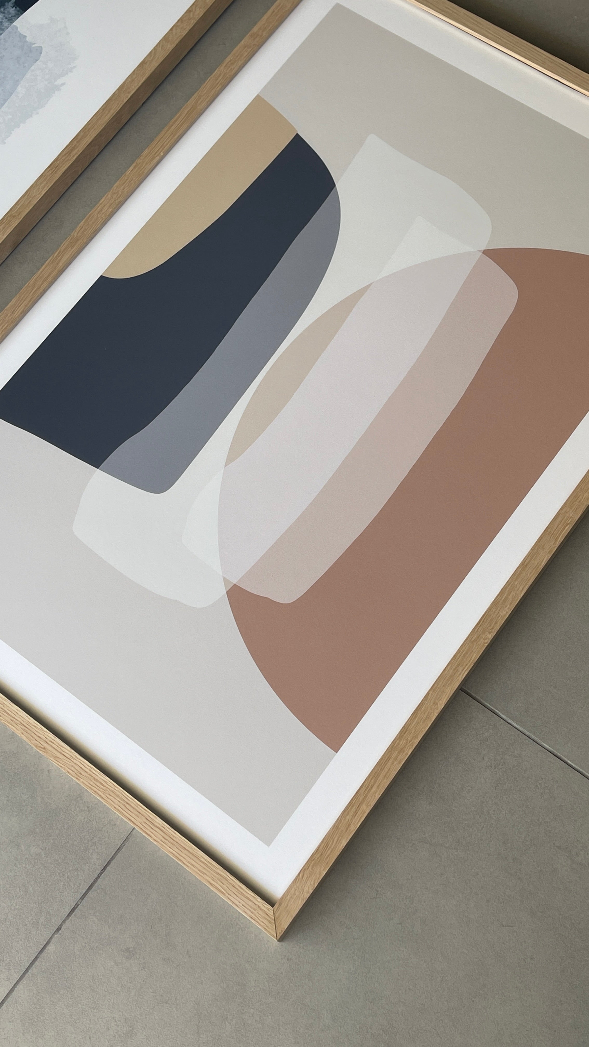 סט של שני פוסטרים ממוסגרים בסגנון אבסטרקטי, עם צורות אורגניות בגווני בז', כחול עמוק ואפרסק, המשדרים הרמוניה ורוגע.