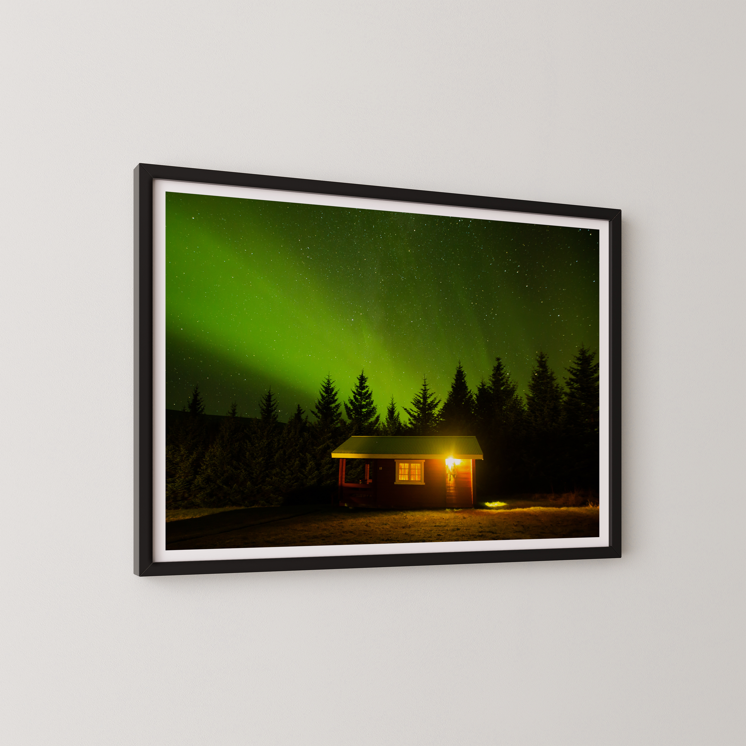 צילום אומנותי של בקתה מוארת בלב היער תחת מופע הזוהר הצפוני באיסלנד, מאת הצלם דניאל עובדיה.