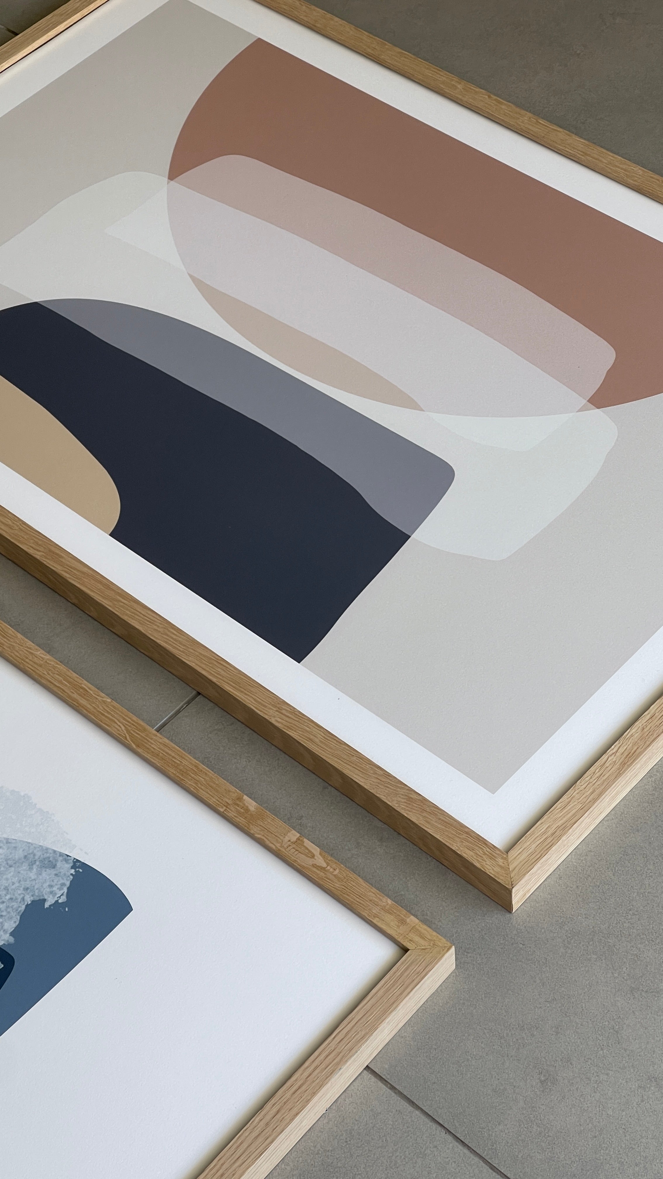 סט של שני פוסטרים ממוסגרים בסגנון אבסטרקטי, עם צורות אורגניות בגווני בז', כחול עמוק ואפרסק, המשדרים הרמוניה ורוגע.