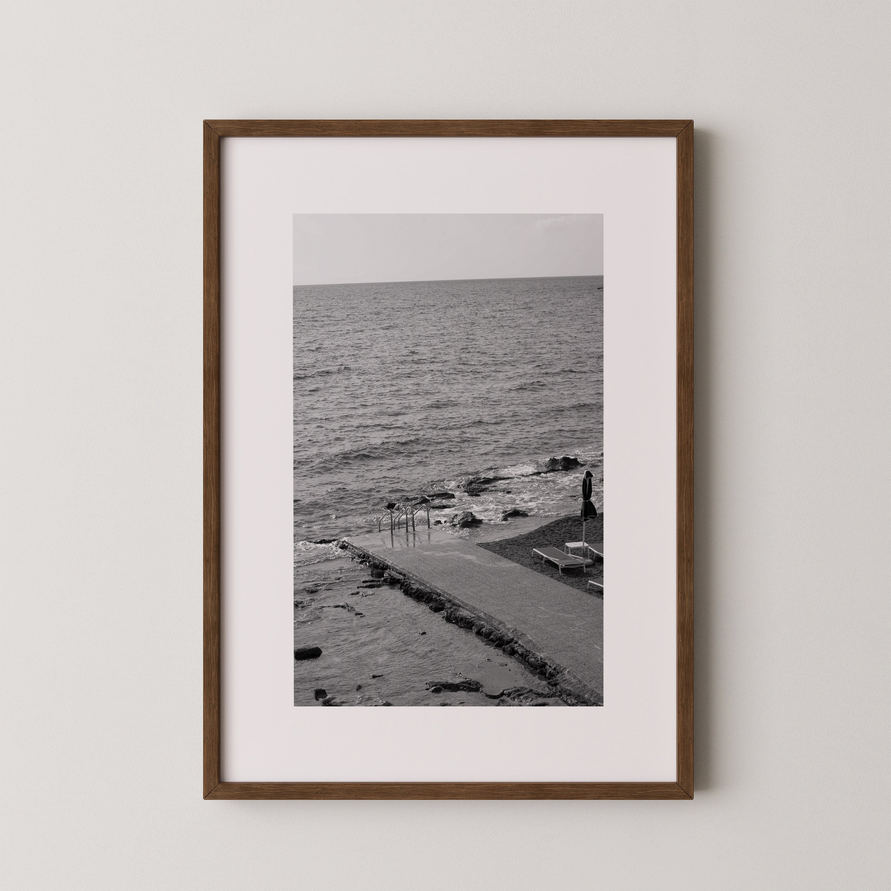 The Quiet Pier by Danielle Berlot – צילום אמנותי בשחור־לבן של מזח שקט היוצא אל הים ברודוס, במסגרת עץ אלון.
