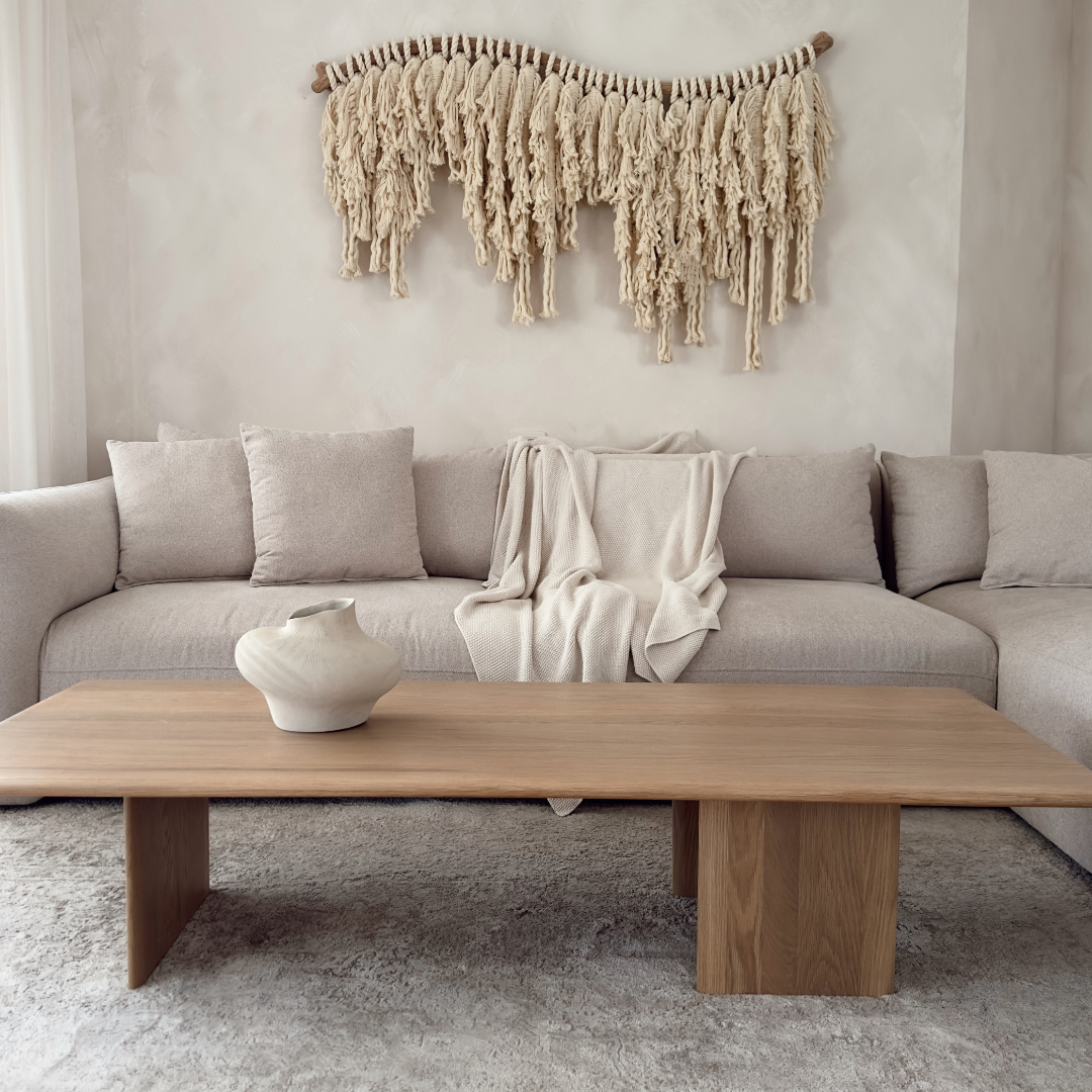 יצירת קיר מדגם דיאניס מבית Cotic – חוטי כותנה טבעיים במרקם פראי, תלויים על מוט עץ בגימור טבעי, על רקע קיר בהיר
